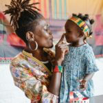 Mother and daughter share a playful moment in colorful traditional clothing indoors.